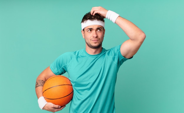 Homem de fitness se sentindo perplexo e confuso, coçando a cabeça e olhando para o lado