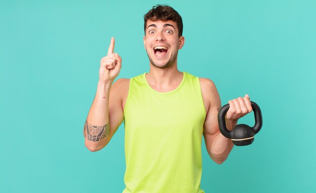 Homem de fitness se sentindo um gênio feliz e animado depois de realizar uma ideia, levantando o dedo alegremente, eureka!