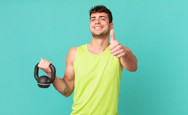 Homem de fitness sentindo-se orgulhoso, despreocupado, confiante e feliz, sorrindo positivamente com o polegar para cima