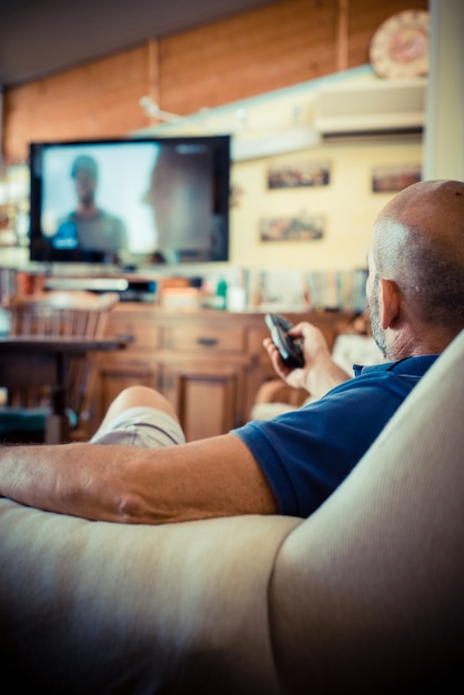 homem de idade miggle assistindo tv