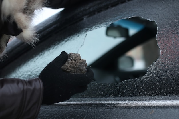 Homem de inverno vandalismo quebrou o vidro do carro uma pedrinha