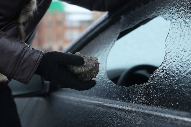 Homem de inverno vandalismo quebrou o vidro do carro uma pedrinha