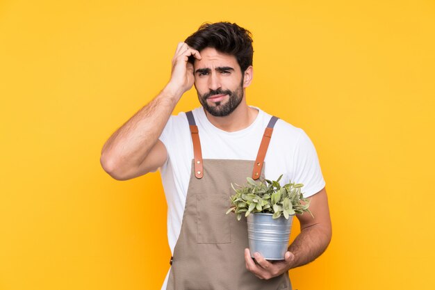 Homem de jardineiro com barba sobre parede amarela isolada infeliz e frustrada com algo. Expressão facial negativa