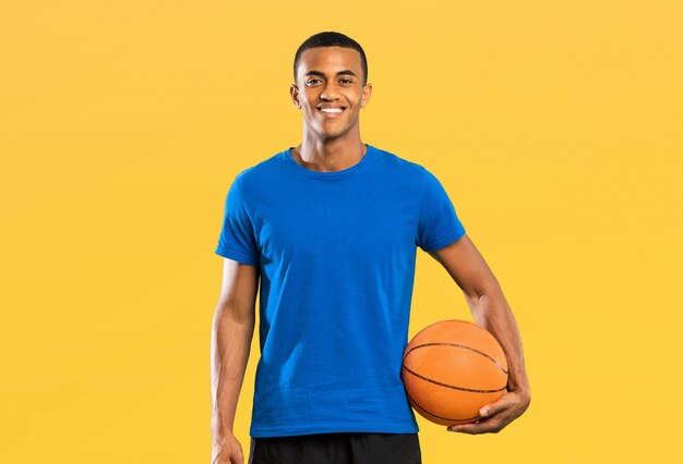 Homem de jogador de basquete afro-americano sobre parede amarela isolada