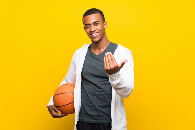 Homem de jogador de basquete americano africano, convidando para vir com a mão. Feliz que você veio