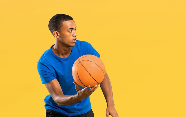 Homem de jogador de basquete americano afro sobre amarelo isolado
