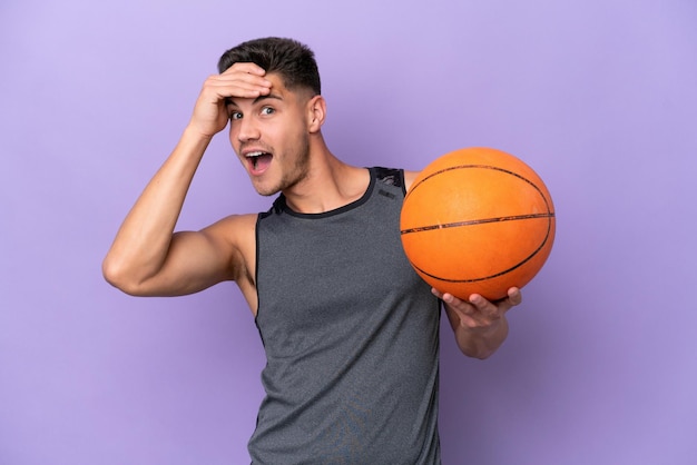 Homem de jogador de basquete jovem caucasiano isolado no fundo roxo fazendo gesto de surpresa enquanto olha para o lado