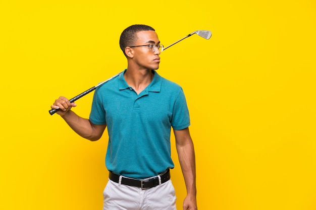 Homem de jogador de golfe americano afro sobre amarelo isolado