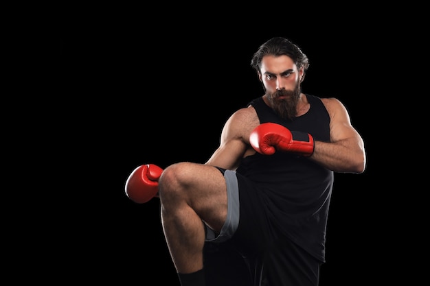 Homem de kickboxer lutando contra um fundo preto. Conceito de esporte.