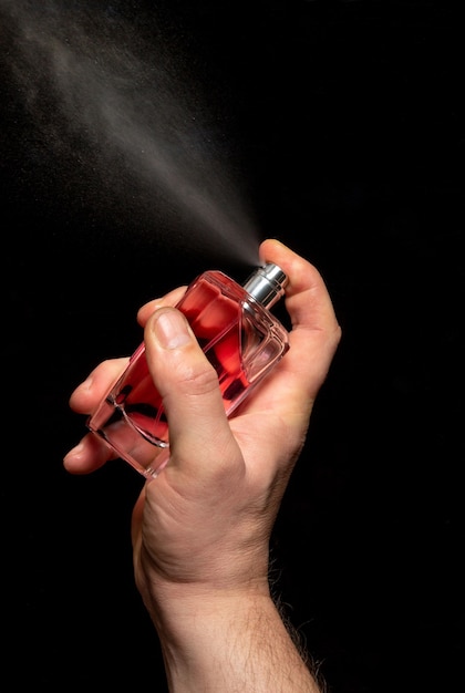 Homem de mão espalhando perfume em fundo preto