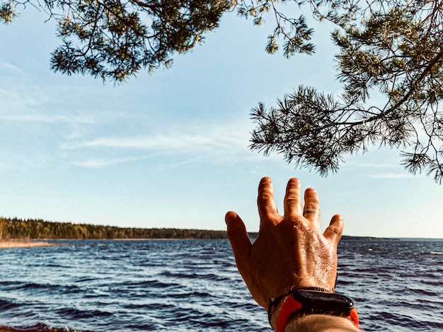 Homem de mão pelo mar contra o céu