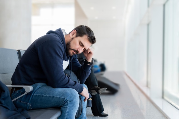 Foto homem de meia-idade a dormir numa sala de espera cansado de esperar pelo comboio, pelo avião, pelo médico.