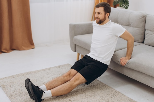 Homem de meia-idade barbudo atlético positivo se alongando em casa usando laptop assistindo a vídeos esportivos na Internet com espaço de cópia on-line de aula de fitness Esporte de estilo de vida saudável em auto-isolamento