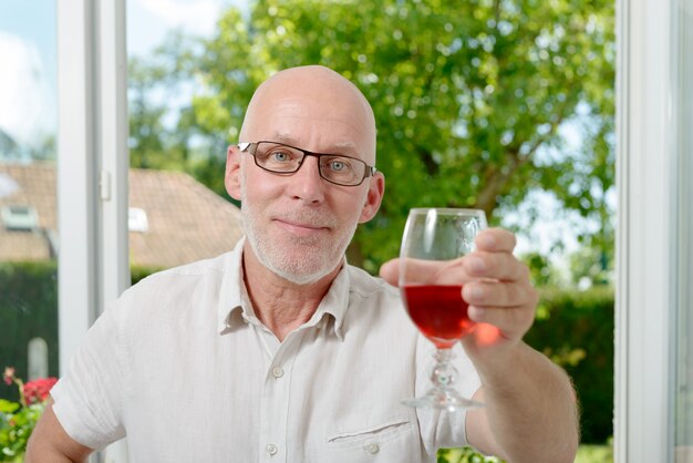 Homem de meia idade, bebendo um copo de vinho