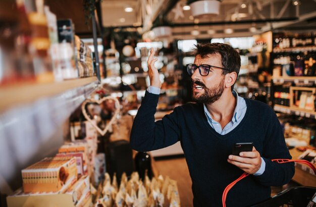 Homem de meia-idade bonito, comprando comida e bebida saudáveis em um supermercado moderno ou mercearia. Conceito de estilo de vida e consumismo.