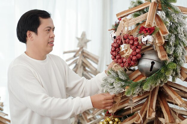 Homem de meia idade decorando árvore de Natal na sala de estar