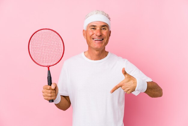 Homem de meia idade jogando badminton isolado pessoa apontando à mão para um espaço de cópia de camisa, orgulhoso e confiante