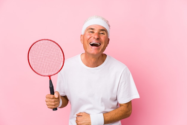 Homem de meia idade jogando badminton isolado rindo e se divertindo.