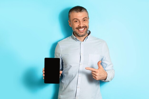 Homem de meia idade mostrando fundo azul de tela em branco de tablet digital