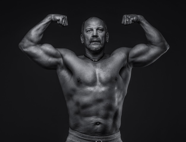 Homem de meia idade muscular posando no estúdio. Isolado em cinza