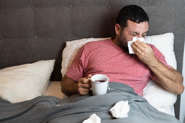 Homem de meia-idade na cama doente com sintomas de gripe.