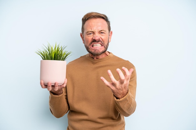 Homem de meia-idade parecendo zangado, irritado e frustrado. conceito de vaso de planta