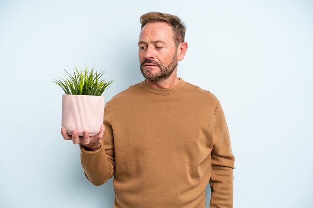 Homem de meia idade se sentindo triste, chateado ou com raiva e olhando para o lado. conceito de vaso de planta