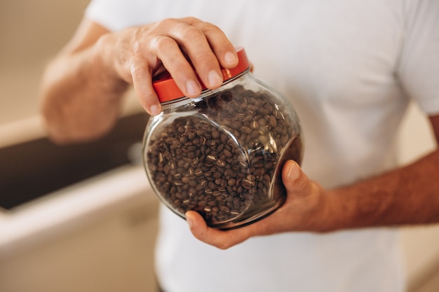 Homem de meia-idade segurando um pote de grãos de café