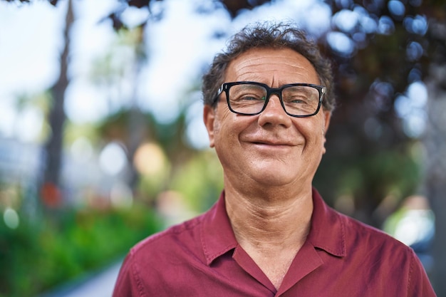 Homem de meia-idade sorrindo confiante em pé no parque