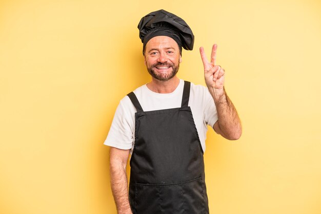 Homem de meia idade sorrindo e parecendo amigável, mostrando o número dois. conceito de chef