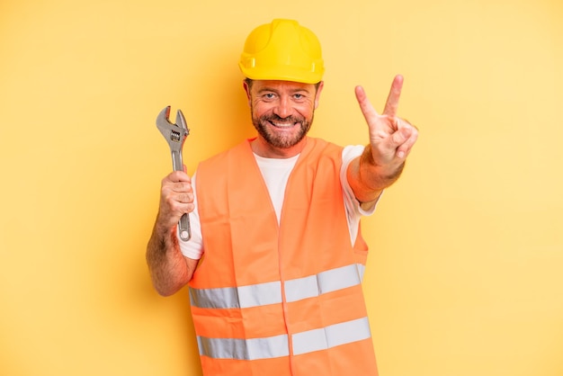 Homem de meia idade sorrindo e parecendo feliz, gesticulando vitória ou paz. conceito de chave de reparo de carro de avaria