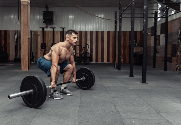 Homem de musculação muscular fazendo exercício de levantamento terra com uma barra pesada em um clube de saúde moderno. Musculação e Fitness