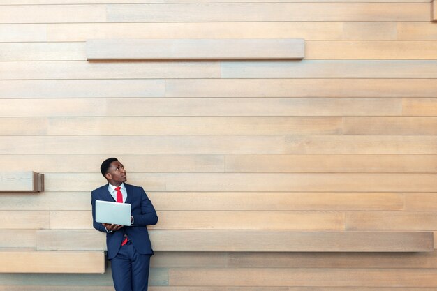 Homem de negócio africano esperto que usa o portátil no escritório. Copyspace