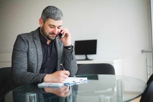 Homem de negócio que senta-se na mesa e no contrato de assinatura.