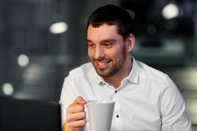 Homem de negócios a beber café à noite no escritório.