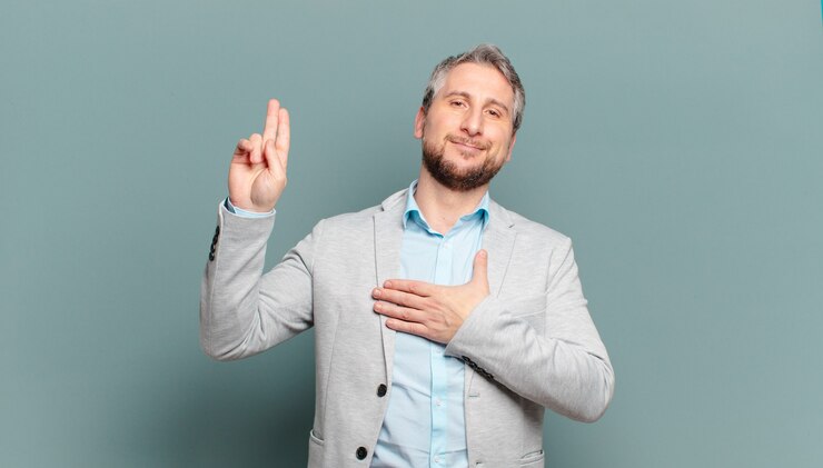 Foto homem de negócios adulto parecendo feliz, confiante e confiável, sorrindo e mostrando sinal de vitória, com uma atitude positiva