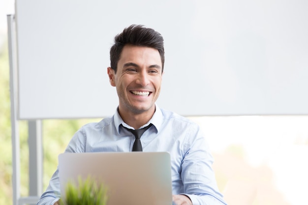 Homem de negócios alegre olhando para longe enquanto trabalha no escritório