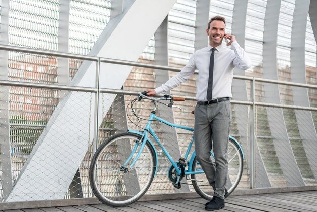 Homem de negócios ao lado de sua bicicleta vintage falando no celular