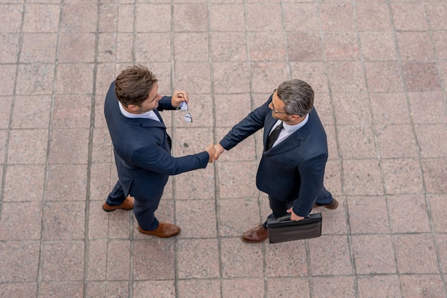 Foto homem de negócios apertando as mãos de dois empresários aperto de mão aperto de mão ao ar livre pessoas de negócios aperto de mão de