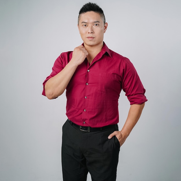 Homem de negócios asiático bonito musculoso carregando uma parede cinza isolada séria