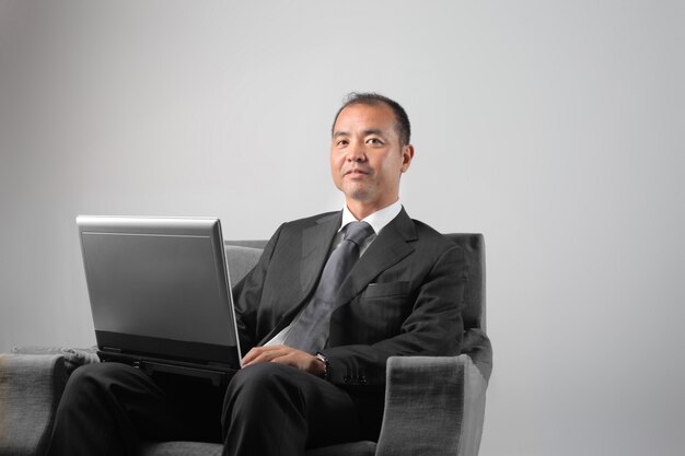 Homem de negócios asiático com um laptop