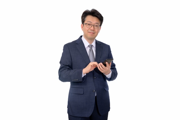 Homem de negócios asiático da meia-idade que usa um smartphone móvel em um fundo branco.