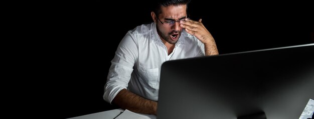 Foto homem de negócios asiático fatigado que sente sonolento e que boceja ao trabalhar o turno da noite