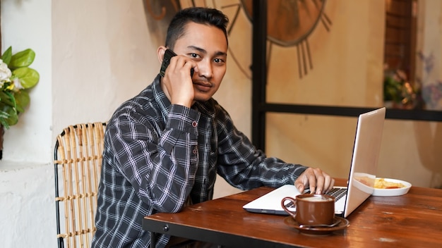 Homem de negócios asiáticos ligando e trabalhando em um café