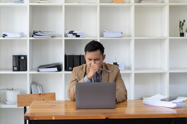 Homem de negócios asiáticos se sentindo estressado e frustrado ao trabalhar com computador portátil Empreendedor masculino tendo problemas com seu estilo de vida freelance de trabalho no espaço de trabalho urbano