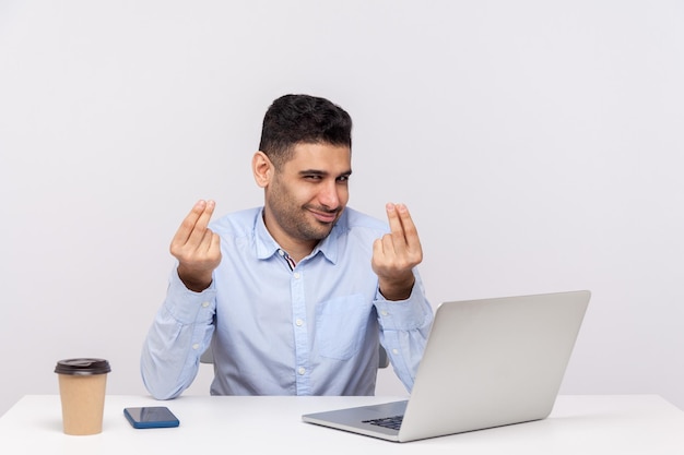 Homem de negócios astuto inteligente sentado no local de trabalho do escritório com laptop na mesa sorrindo com expressão astuta e mostrando gesto de dinheiro planejando grande lucro tiro de estúdio interno isolado no fundo branco