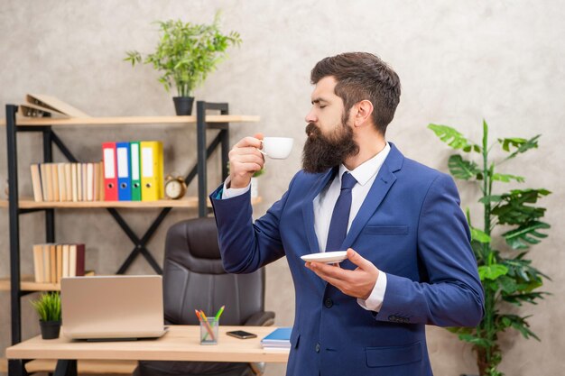 Homem de negócios barbudo sério cheira café no escritório com empresário de espaço de cópia