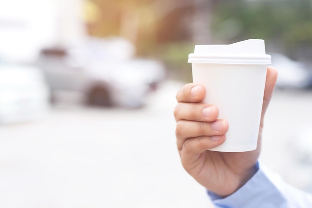 Foto homem de negócios bebendo bebida copo de papel café quente na mão enquanto está de lado antes de dirigir um veículo na luz solar da manhã transporte e conceito de veículo