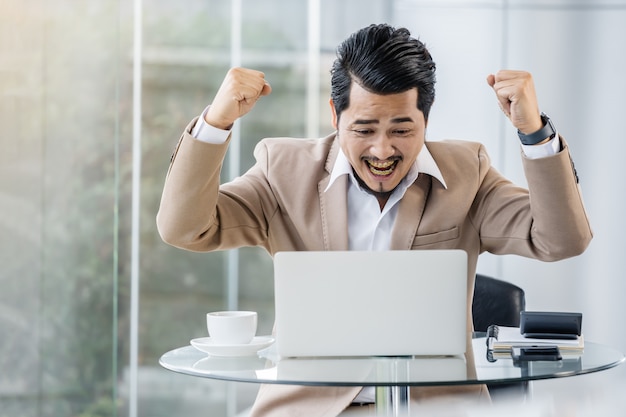 Homem de negócios bem sucedido feliz usando computador portátil