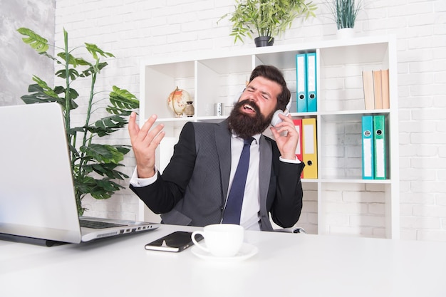 Homem de negócios bem sucedido trabalhador de escritório ouvindo música fones de ouvido bom humor e inspiração música motivacional agente de seguros contabilista relaxante com música favorita conceito de produtividade